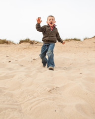 boy running down a sand dune