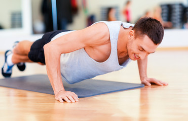 Naklejka na ściany i meble smiling man doing push-ups in the gym