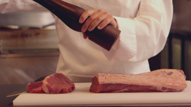 Chef seasoning a piece of beef
