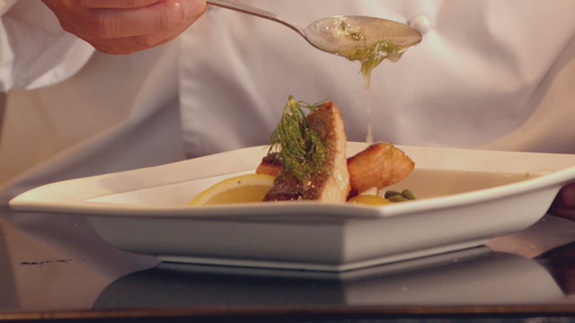 Chef pouring sauce over fish dish
