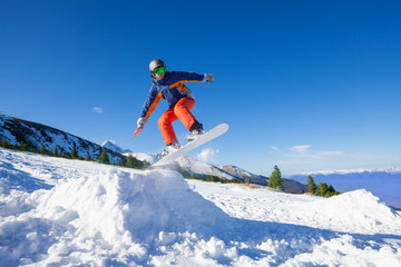 Snowboarder jumping high from hill in winter