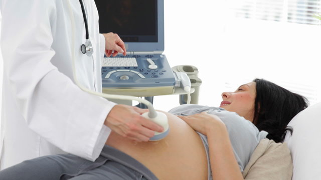 Brunette pregnant woman having a sonogram scan
