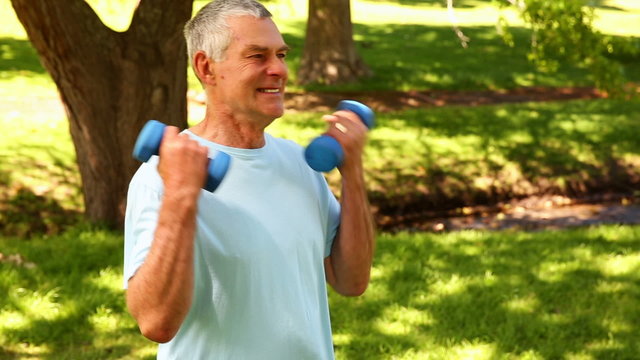 Retired man lifting weights outside