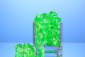 A glass with green decorative stones on blue background