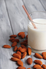 Almond milk in glass with almonds in bowl,