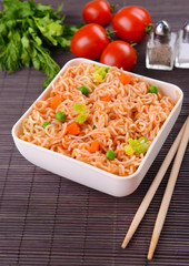 Tasty instant noodles with vegetables in bowl on table close-up