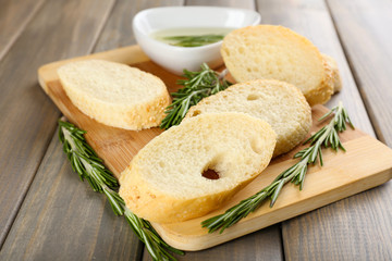 Fresh bread with olive oil and rosemary on wooden table
