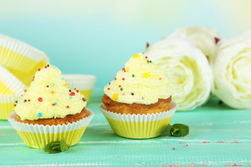 Tasty cup cakes with cream on blue wooden table