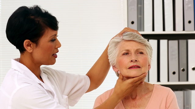 Nurse showing elderly patient how to exercise her injured neck