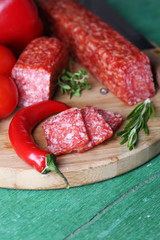 Tasty salami sausage and spices on wooden background