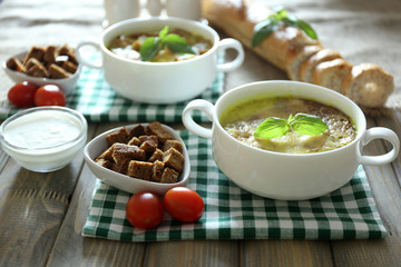 Tasty soup in saucepans on wooden table, close up