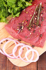 Raw beef meat with spices and greens close up