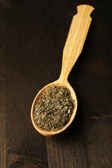 Spice greens in spoon on wooden background