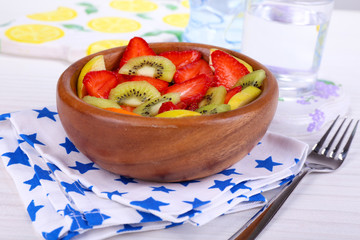 Various sliced fruits in bowl on table close-up