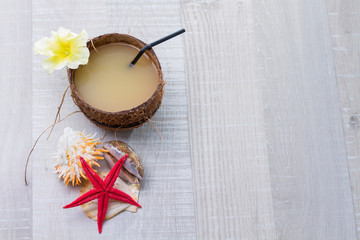 Coconut cocktail, starfish and shells on the deck
