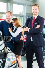 Verkäufer und Kunden mit Auto im Autohaus