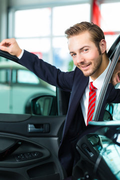 Verkäufer mit Auto im Autohaus