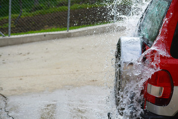 agua golpeando la parte trasera de un coche rojo