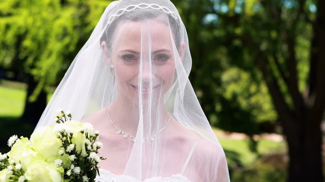Pretty bride smiling at camera with veil over her face
