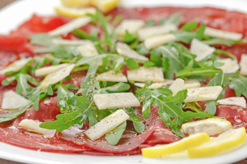 Closeup bresaola with arugula salad and olive oil