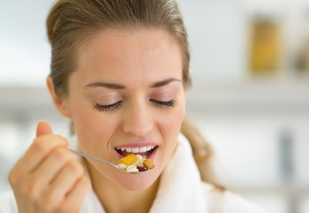 Portrait of young woman eating muesli in kitchen