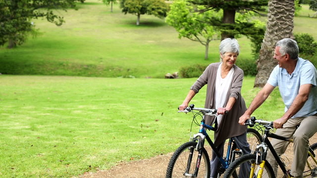 Retired couple in the park riding their bikes