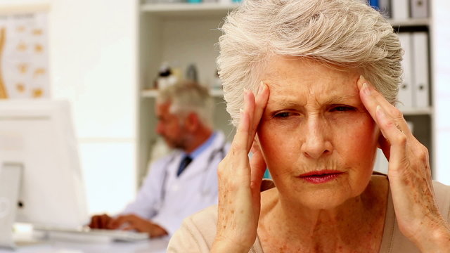 Senior woman with a bad headache visiting the doctor