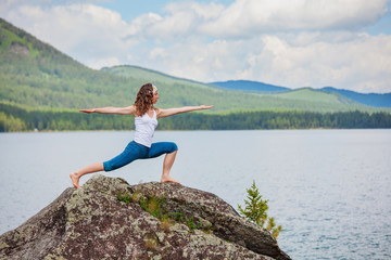 Naklejka na ściany i meble Young woman is practicing yoga at mountain lake