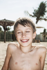 Fototapeta na wymiar Beautiful cheerful child tanning on sandy beach laughing