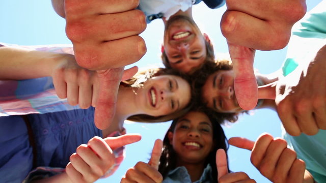 Students putting heads together and giving thumbs up to camera