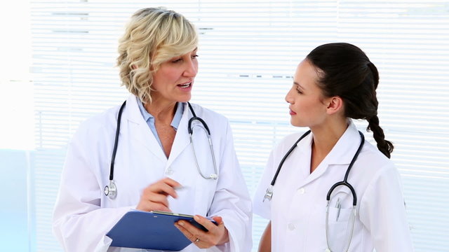 Doctor and nurse discussing something on clipboard