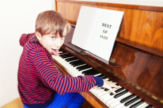 Beatiful funny child playing piano looking into camera