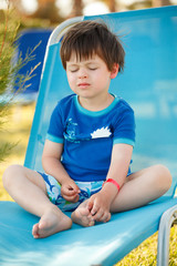 Cute toddler boy sitting on a sunbed