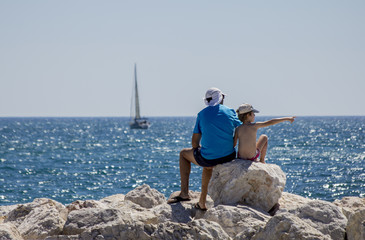 Padre con hijo sentados frente al mar