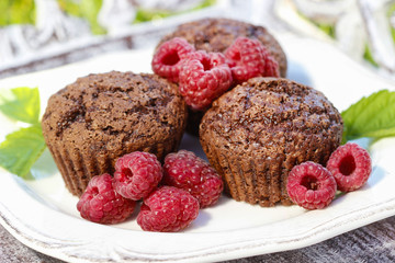 Muffins with fresh raspberries on wooden tray in the garden