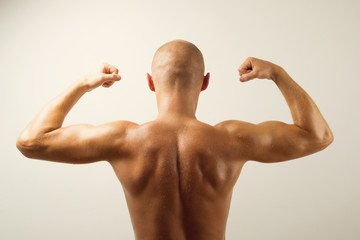 Rear view of muscular man showing his back muscles - Powered by Adobe