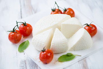 Sliced adygea cheese, baked cherry tomatoes and fresh mint