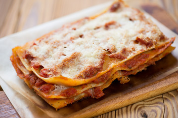 Meat and cheese lasagna over rustic wooden background