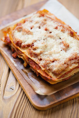 Rustic wooden cutting board with meat lasagna, close-up