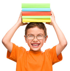 Little boy is holding a pile of books