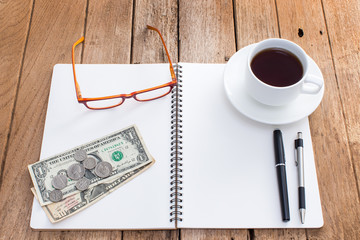 Blank notebook with pen and coffee cup on old wooden background