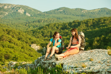 Two women is trekking in the Crimea mountains with backpacks