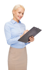 smiling businesswoman with clipboard and pen