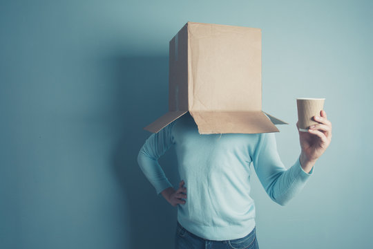 Man with cardboard box over head and a cup