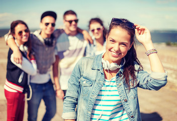 teenage girl with headphones and friends outside