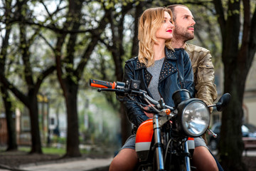 Couple sitting on the motorcycle in the city park