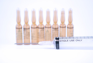 Disposable syringe and brown injection ampule background