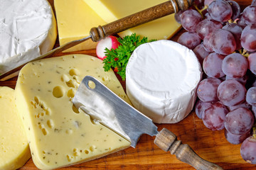A plate with different kinds of cheese and grapes