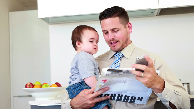 Father carrying his baby son before work and talking on phone
