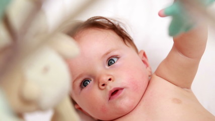 Cute baby playing with mobile in his crib